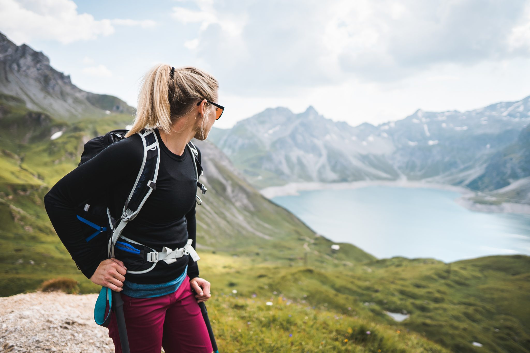 Femme en montagne regardant vers un lac derrière elle